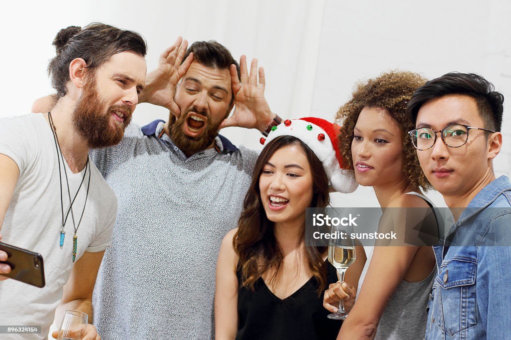 Friends celebrating birthday Friends celebrating birthday and taking selfie in party Christmas Stock Photo