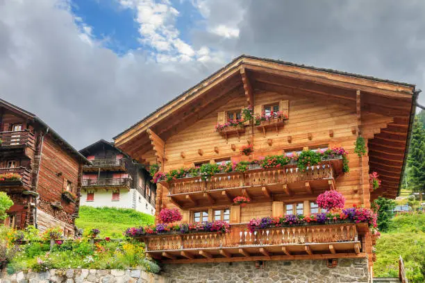 Beautiful traditional wooden houses in the alpine village Grimentz, Switzerland, in the canton Valais, municipality Anniviers, with geranium flowers on the balconies