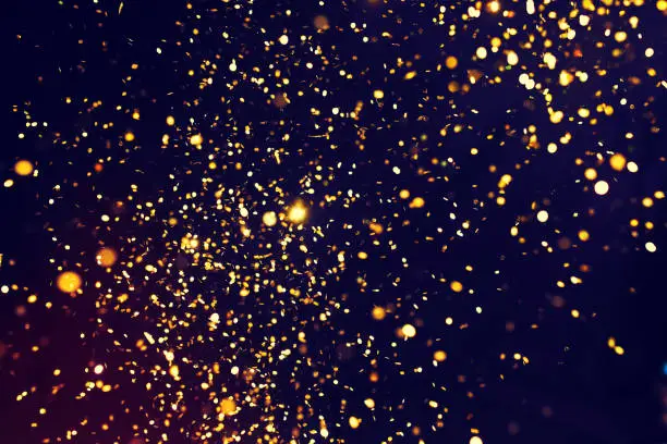 Photo of golden glitter on a black background. Golden explosion of confetti. Holiday background