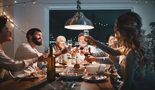 Closeup side view of a family having a Christmas eve dinner. They are having some traditional roast, gravy and vegetables and also some vegetarian food. There are three men and four women at the table having casual conversation.