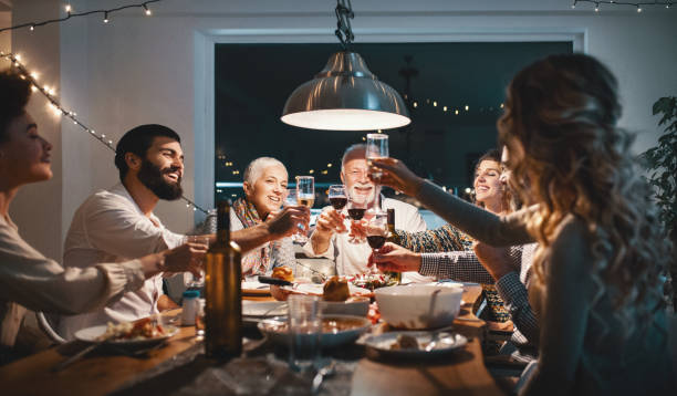 Family having dinner on Christmas eve. Closeup side view of a family having a Christmas eve dinner. They are having some traditional roast, gravy and vegetables and also some vegetarian food. There are three men and four women at the table having casual conversation. white wine photos stock pictures, royalty-free photos & images