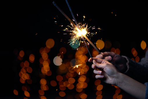 Unrecognizable romantic couple celebrating Christmas together and lighting sparklers