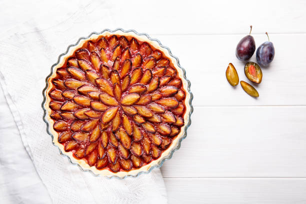 Homemade plum pie. Fruit tart on white table. Copy space. Top view.