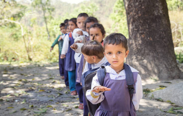 Village elementary school kids forming line for morning prayer. different age group children wearing school uniform.