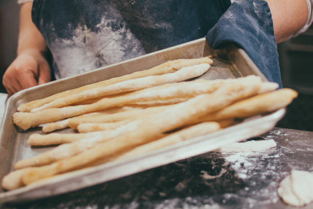 Breadstick - Grissini in the making. Ready for the oven. On a hot plate.