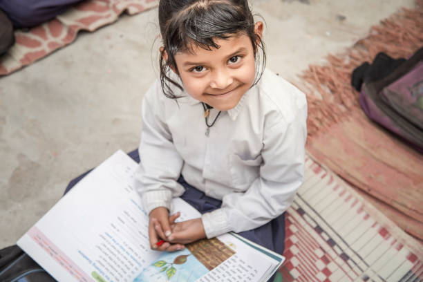 entzückende glücklich vorschulkind mädchen, lehrbücher, schulbücher zu lesen. tragen schuluniform. - poverty india child little girls stock-fotos und bilder