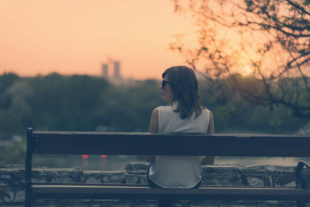 istock Woman sitting on a bench and watching the distant city scenery. 896372088