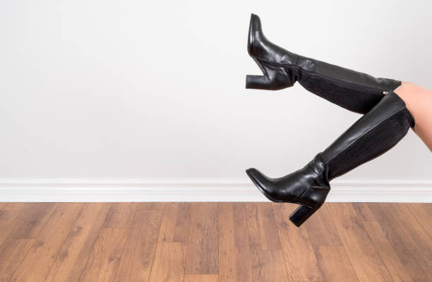 Woman Modelling Black Knee High Leather Boots Woman Modelling Black Knee High Leather Boots Against a Light Grey Wall legs against the wall stock pictures, royalty-free photos & images