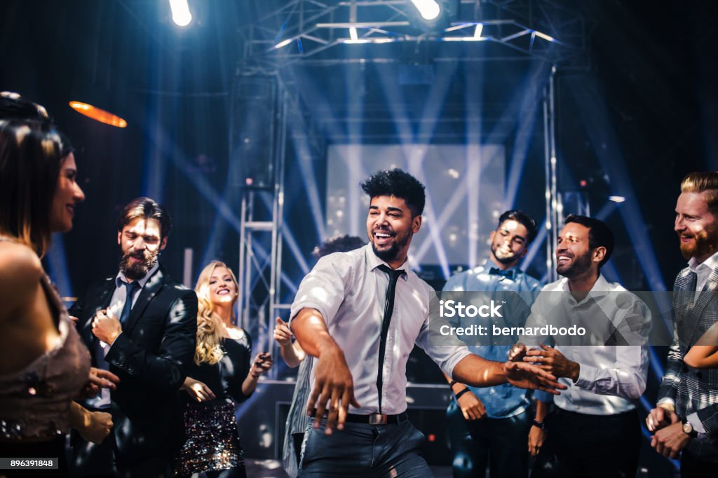That's my jam ! Shot of a young man on the dancefloor with friends Dancing Stock Photo
