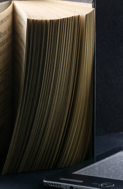 istock The old parted book is close-up in the backlight with a clearly defined page texture and a modern e-book. 896405742