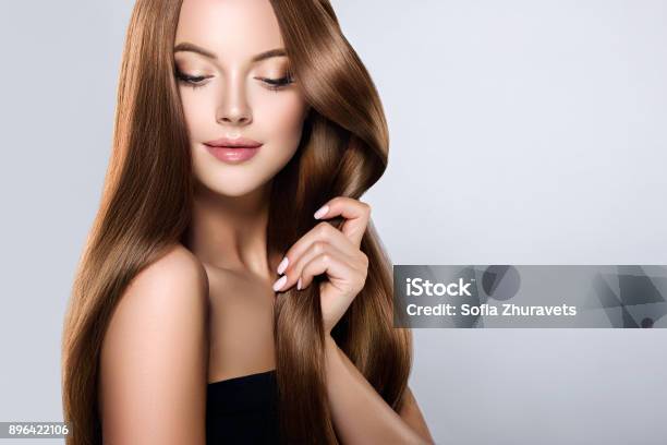 Young Brown Haired Beautiful Model With Long Straight Well Groomed Hair Is Touching Own Hair With Tenderness Stock Photo - Download Image Now