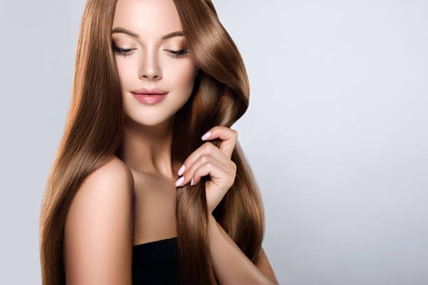 young, brown haired beautiful model with long,  straight, well groomed hair is touching own hair with tenderness. - hair care imagens e fotografias de stock
