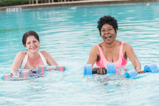 istock Two mature multi-ethnic women doing water aerobics 896453162
