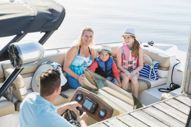 Family on a boat A family with two children sitting on a boat, smiling. The boy is 5 years old and his sister is 11. family motorboat stock pictures, royalty-free photos & images