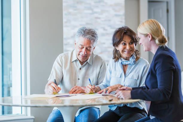 istock Senior couple talking with a personal advisor, signing papers 896461120