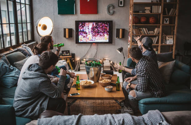Friends are having great weekend Group of friends watching basketball game on tv at home. tv game stock pictures, royalty-free photos & images