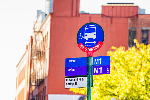 New York City Bus stop sign with disabled access illustration. Blurred apartment building in the background.