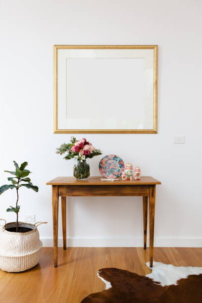 istock Blank picture frame above a side table with flowers and pot plant 896553454