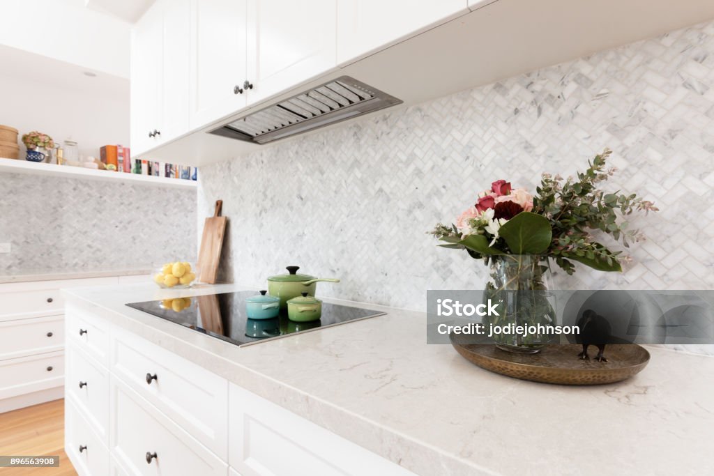 Rear kitchen bench styled with cut flowers and colorful saucepans Kitchen Stock Photo