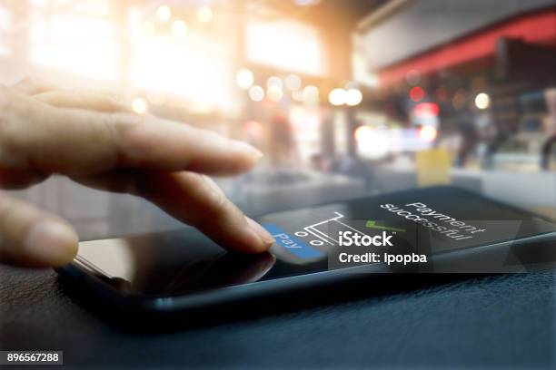 Hand Touching Mobile Screen Of A Payment Successful Message On Shopping Mall Background Stock Photo - Download Image Now