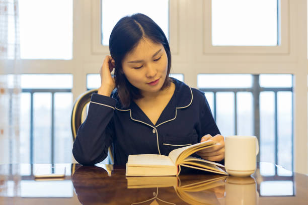 istock woman reading a book by dining table 896586964