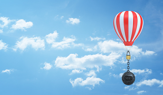 3d rendering of a striped hot air balloon flies in the sky weighted down by a wrecking ball with a word Debt written on it. Weight of credit. Financial burden. Travelling expenses.