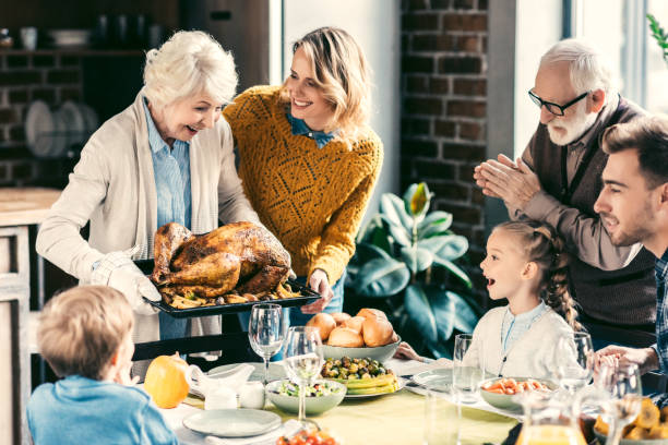 family having holiday dinner beautiful grandmother carrying turkey for family on thanksgiving dinner thanksgiving holiday travel stock pictures, royalty-free photos & images