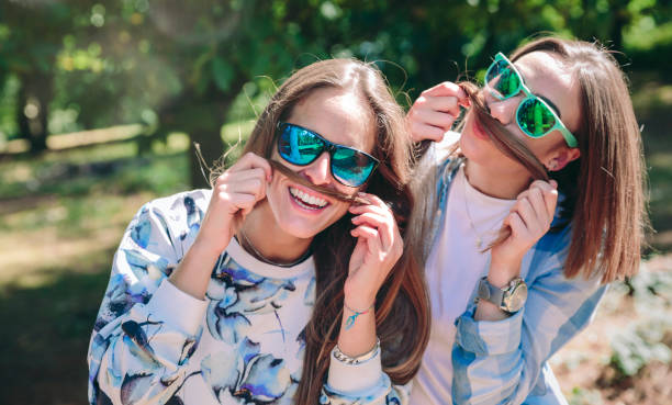 istock Women doing moustaches with hair and laughing 896676652