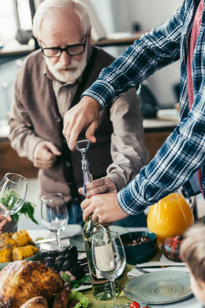 istock senior and young men opening wine 896684266