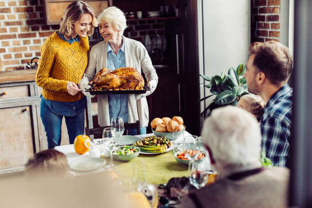 senior woman and her daughter with turkey senior woman and her daughter carrying turkey for thanksgiving dinner with their large family thanksgiving holiday travel stock pictures, royalty-free photos & images