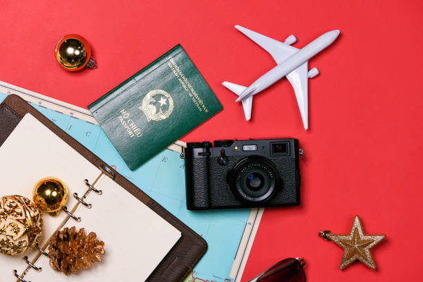 istock Preparation for travel concept - passport, camera, hat, airplane, chrismas decorations on red background 896698028