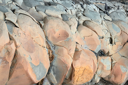 Cracks and colorful layers of sandstone background. A big heap of sandstones, storage space of various natural sandstone. The pattern of the variegated sandstones. Layers of toning colored big stones