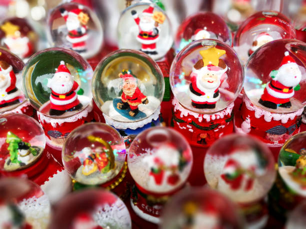 Close up of large collection of christmas snow globes in a row Close up color image depicting a large collection of Christmas snow globes on display and for sale at a christmas market. The ones in the centre are in focus but the ones around the edge are pleasantly defocused. The snow globes contain a figurine of santa claus in various guises. snow globe photos stock pictures, royalty-free photos & images
