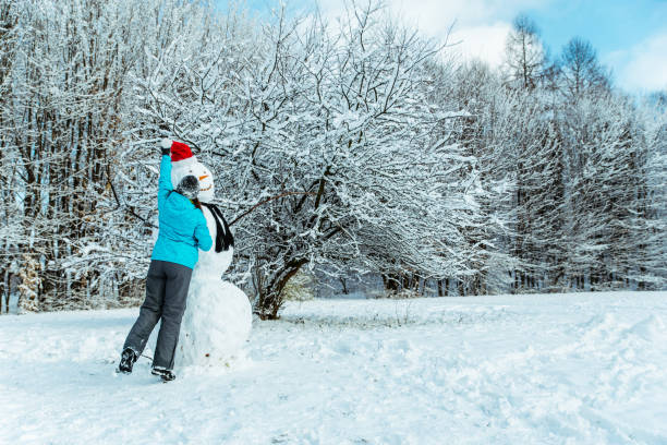 istock woman making snowman in winter day 896741124