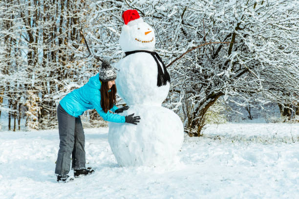 istock woman making snowman in winter day 896741196