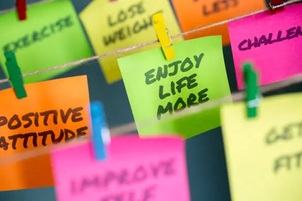 Photo of Sticky notes hanging with important message to enjoy life more