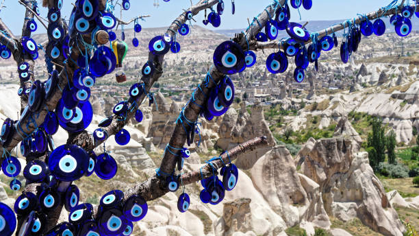 le œil de verre bleu (nazar boncugu) comme moyen de défense contre le mauvais œil, à une branche devant les montagnes de la cappadoce, l’anatolie - nazar boncugu photos et images de collection
