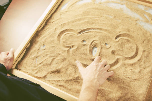 istock a man draws by his  finger on the sand a funny koala. toned. 896756390