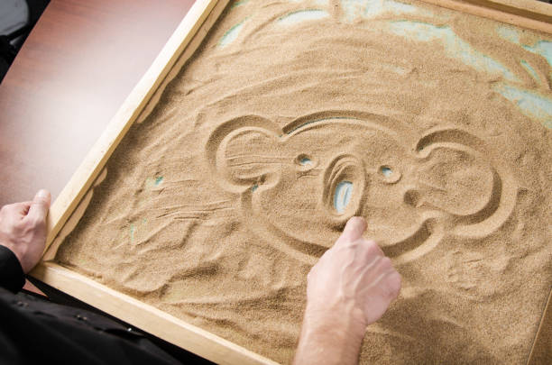 istock a man draws by his  finger on the sand a funny koala. with vignetting. 896758408
