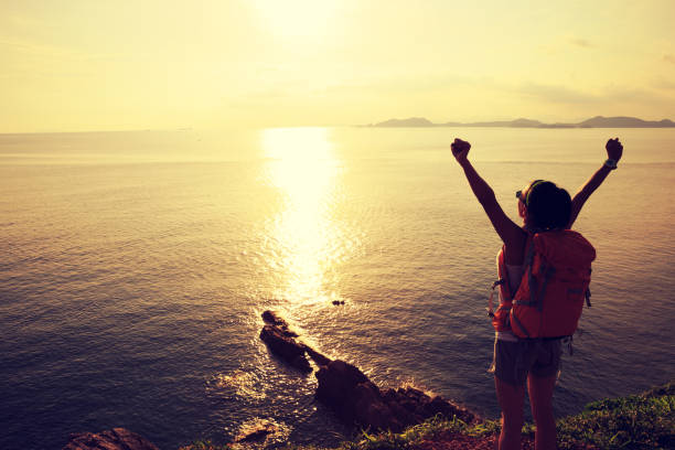 istock Young woman with raised hands standing at sunrise seaside mountain 896761196