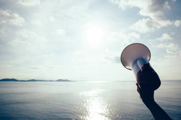 istock Hand hold megaphone against sea under sky background 896761620