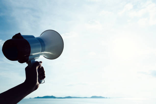istock Hand hold megaphone against sea under sky background 896761740