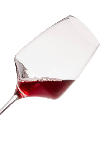 istock Tilted wine glass with red wine. Isolated on white. Close-up. 896764500