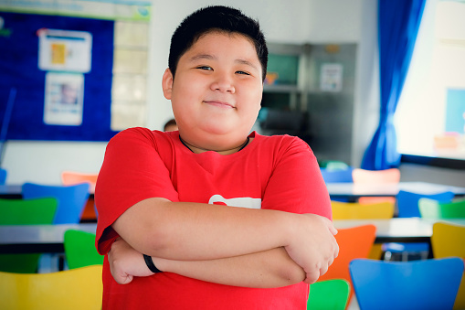 Asian obese boy standing crossed arms and cute smile