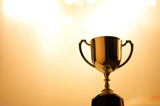istock Gold Trophy competition in the dark on the abstract blurred light background with copy space, Spectacular success Concept 896765348