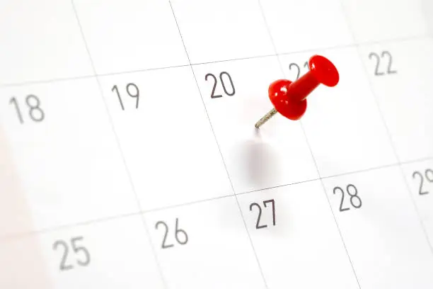 Embroidered red pins on a calendar on the 20th with selective focus