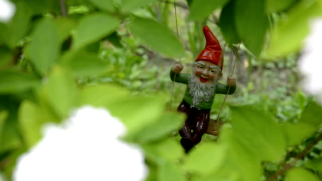 Dwarf in the garden on a swing