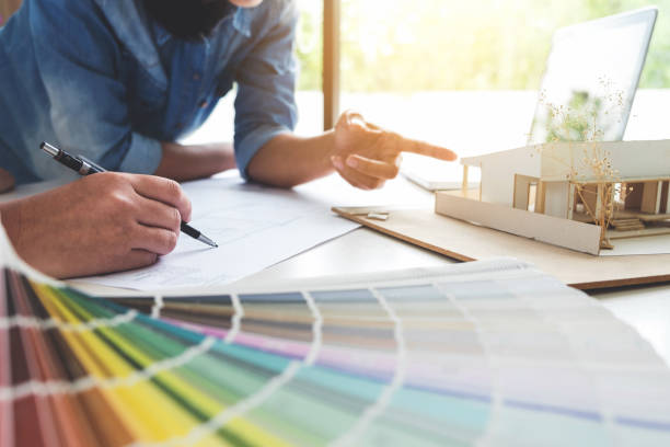 istock Two young women interior design or graphic designer working on project of architecture drawing with work tools and color swatches, colour chart in digital tablet at workplace 896787714