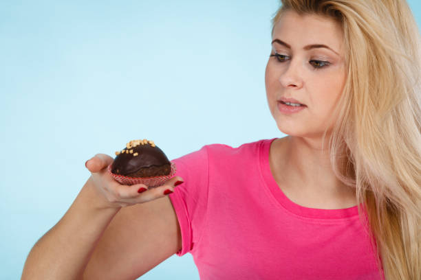 istock Woman holding chocolate cupcake about to bite 896790644