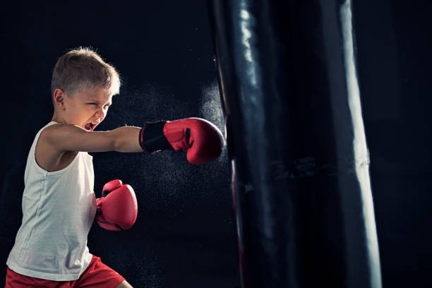 Little boy training boxing with punching bag Little boy training boxing. The boy aged 8 is hitting hard the punching bag.
 violence boxing fighting combative sport stock pictures, royalty-free photos & images